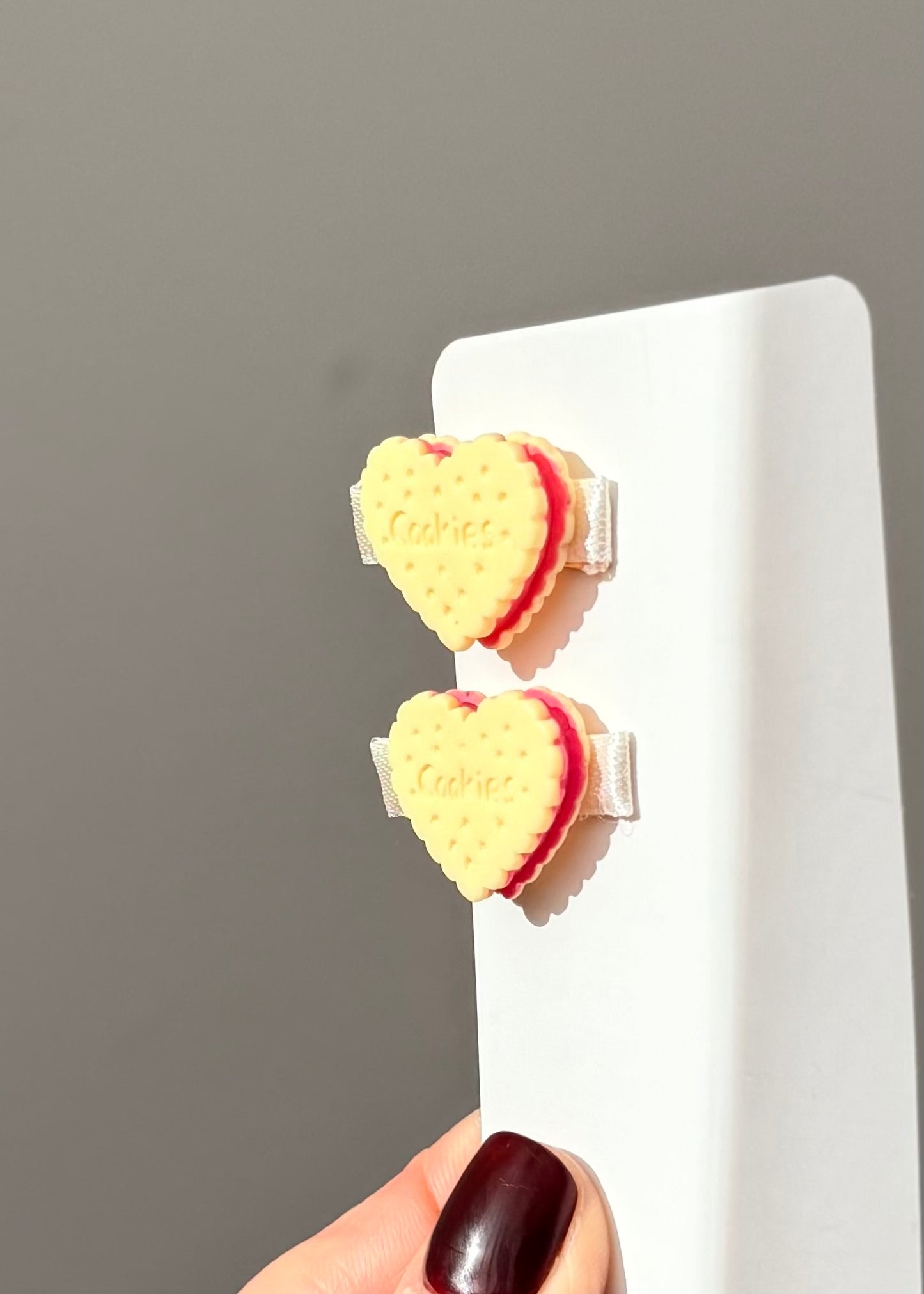Heart-shaped earrings on a white stand against a gray background