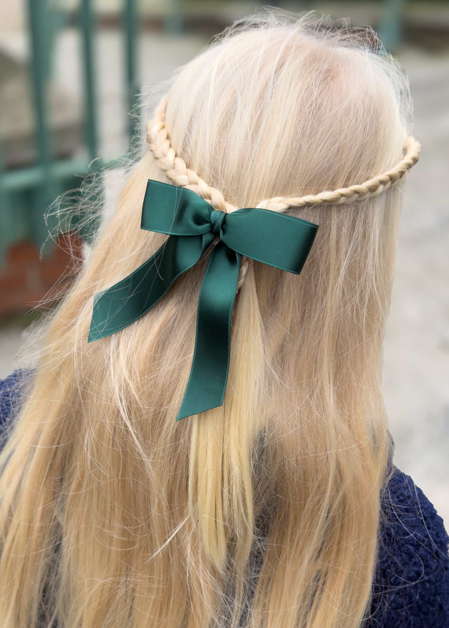 Person with braided hair wearing a green ribbon headband