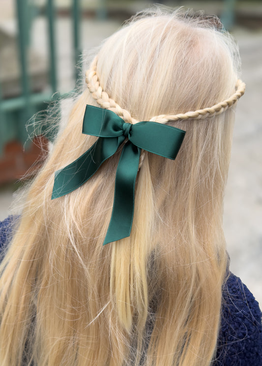 Person with braided hair wearing a green ribbon headband