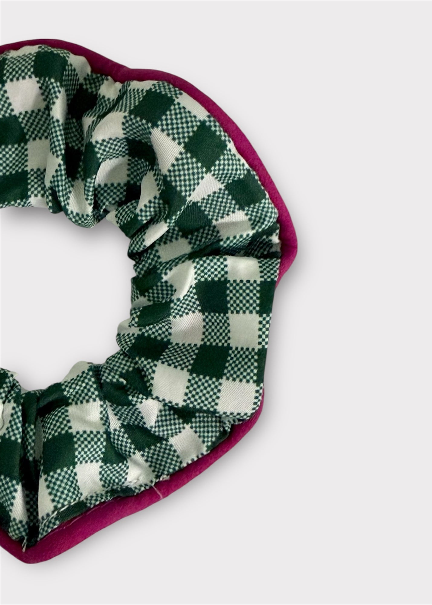Green and white checkered scrunchie with a pink border on a light gray background