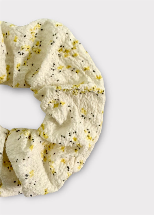 Cream scrunchie with yellow floral pattern on a light gray background