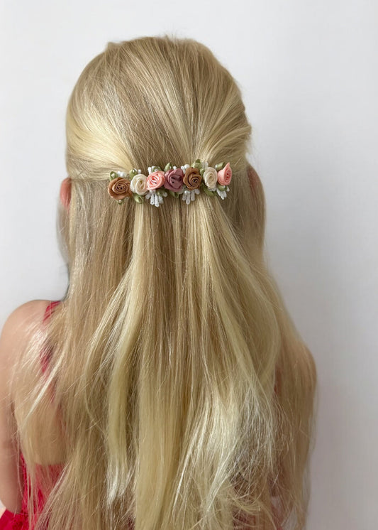 Blonde hair with a floral hair accessory against a white background