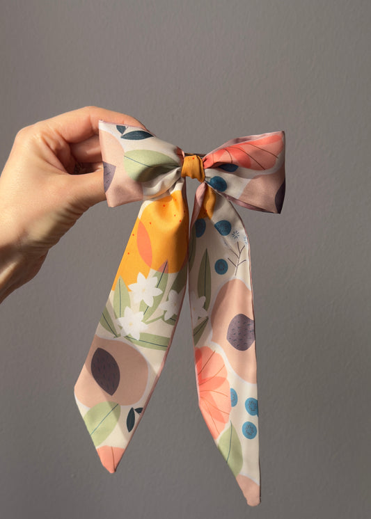 Hand holding a colorful floral ribbon against a gray background