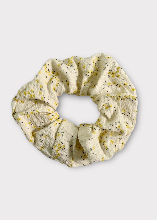 Beige scrunchie with floral pattern on a light gray background